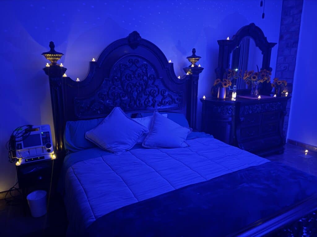 A private treatment room at Freedom Ibogaine in Rosarito, lit in soft blue, with a heart monitor beside the bed