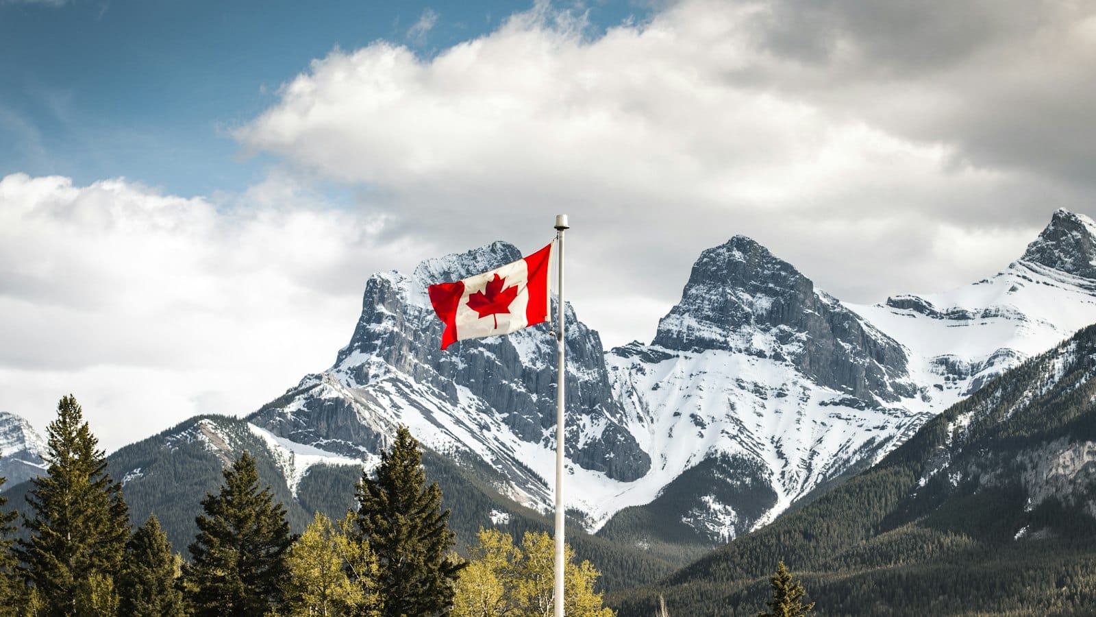 Canadian flag flying in front of the Three Sisters mountains in Canmore, Alberta