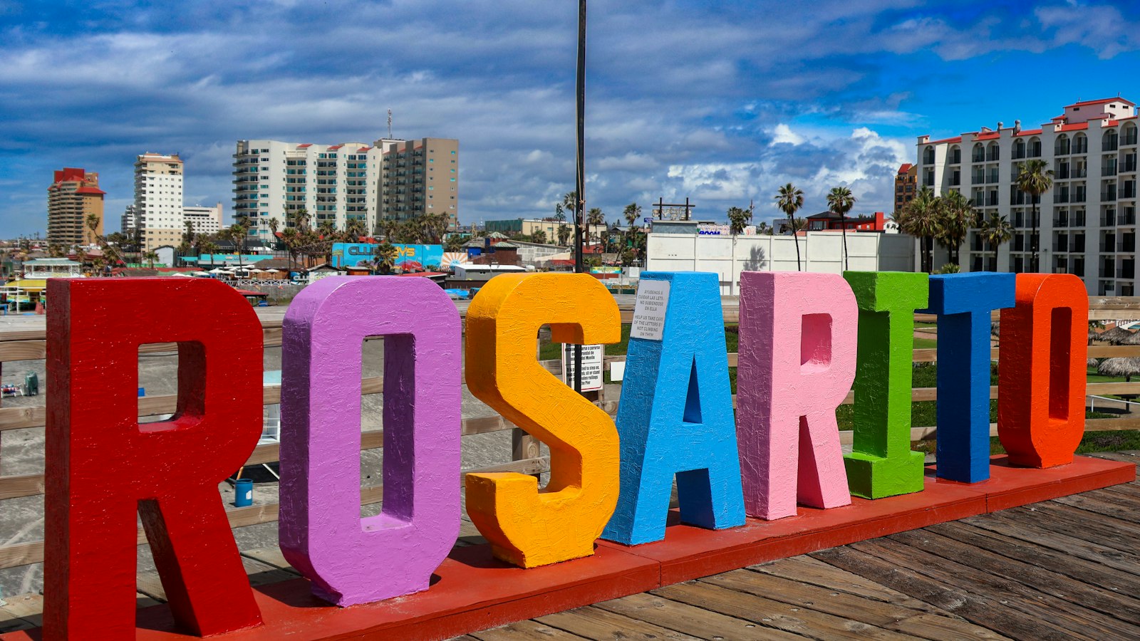 Colorful ROSARITO letters on the boardwalk in Rosarito, Baja California, with hotels behind